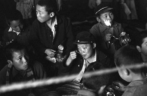 Boys eating food from cans after fire