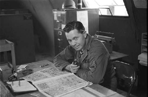 Soldier smoking pipe smiling at camera reading newspaper