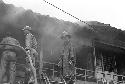 Three firemen in cloud of smoke looking to put out fire