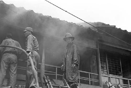 Three firemen in cloud of smoke looking to put out fire