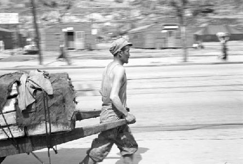 Man pulling loaded cart on street