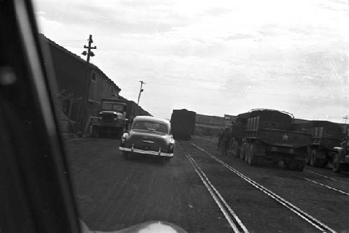 Portrait of car head driving beside train track