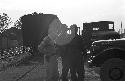 Men near train tracks outside standing by trucks