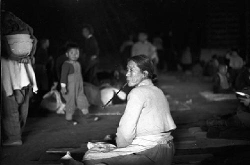 Woman sitting on ground smoking long pipe