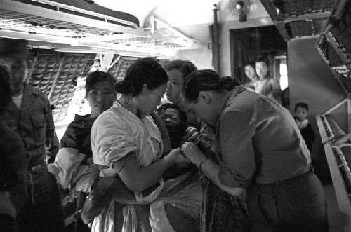 Portrait of baby crying as nurse and woman hold during shot