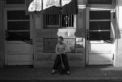 Boy sitting outside of shop