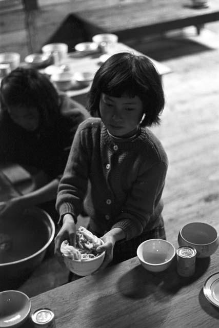 Girl at dinner table holding food in bowl