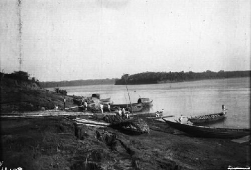 Men preparting canoes along riverbank