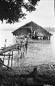 House on stilts over water with log walkway