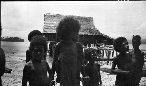 Women and children on the beach with a hut in background