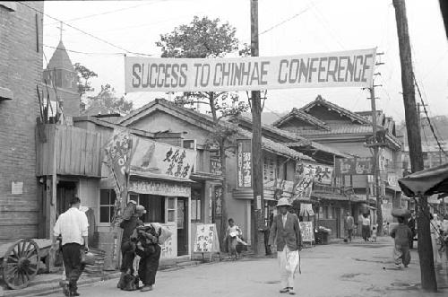 Civilians walking along road with banner hanging above