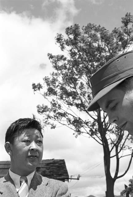 Man in suit standing by another man with top hat on