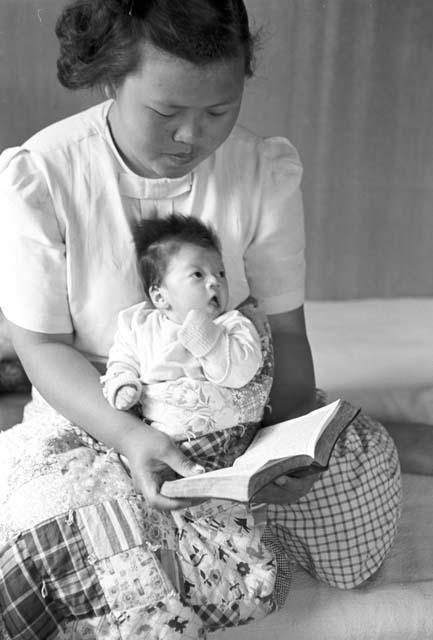 Woman holding baby in lap while reading