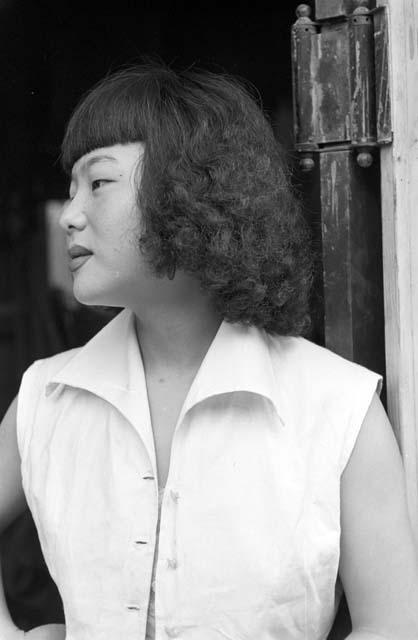 Portrait of woman standing by door wearing white shirt