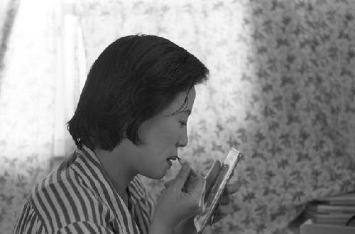 Portrait of woman wearing striped shirt fixing makeup