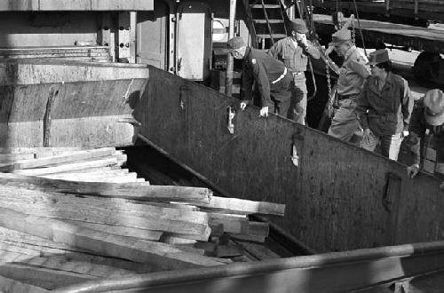 Soldiers looking down observing wood