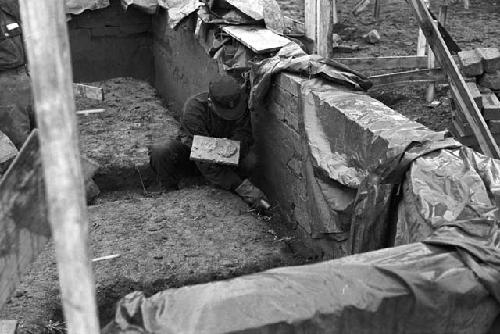 Worker inside ditch smoothing out bricks