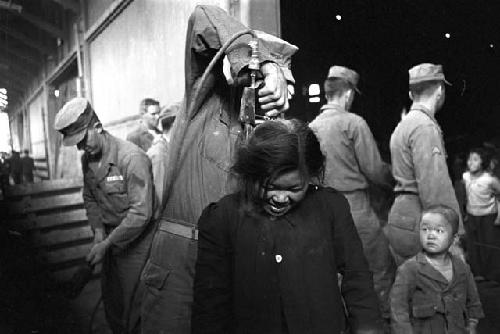 U.S. soldier spraying girl with insecticide