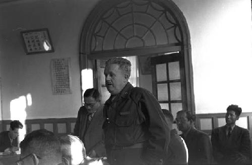 Soldier standing up to speak at table during meeting