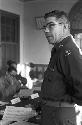 Soldier standing at middle of table holding out document