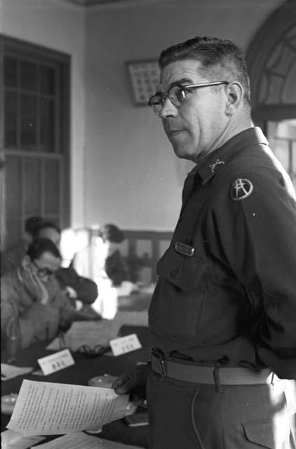 Soldier standing at middle of table holding out document