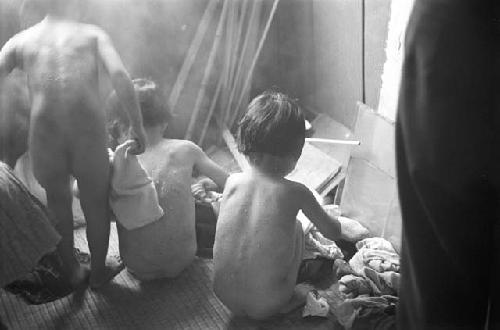 Nude children removing wet clothes