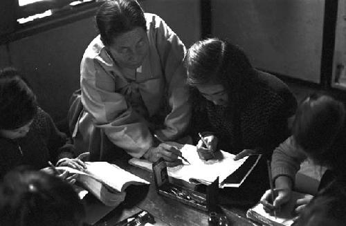 Woman at table helping children with assignment