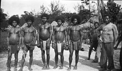 Line of men in loin cloths in village