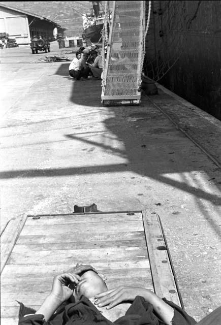 Man sleeping on platform by ship entrance