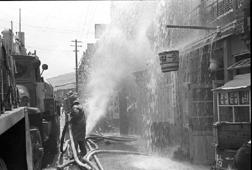 Men getting handle of hose as water sprays onto the store