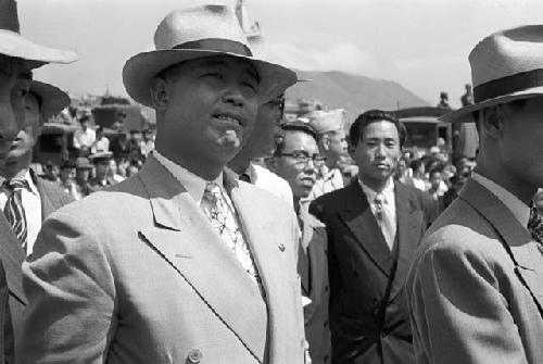 Men in suits at an outdoor gathering