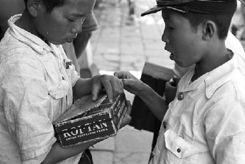 Two boys with box of cigarettes