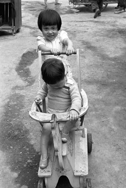 Girl pushing boy in baby carriage