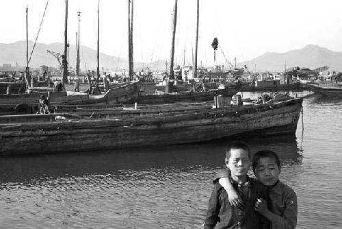 Two boys stand together by boat docks