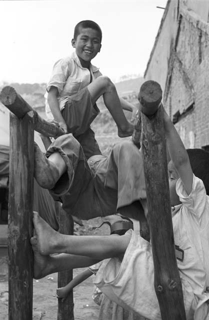 Portrait of children playing on wooden monkey bars