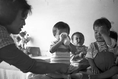 Portrait of woman caring for babies sitting side by side together