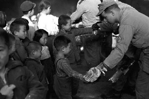 Portrait of children in line waiting to be tagged by soldier