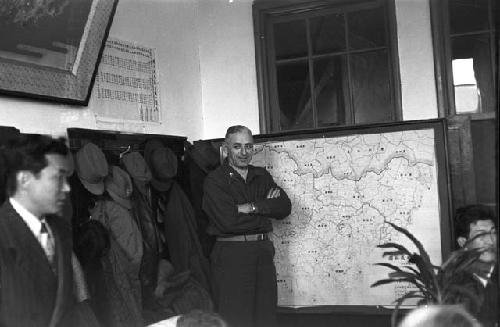 Soldier standing by map while meeting in progress