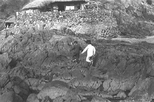 Children walking on rocks together next to water