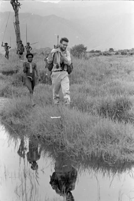 Karl Heider carrying a great deal of equipment from near the Tokolik pond