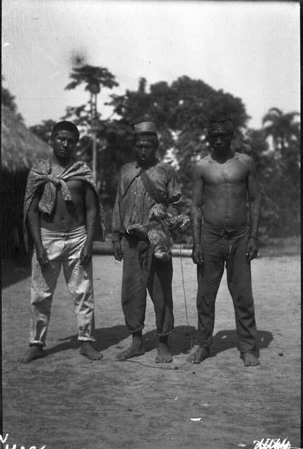 Three men standing with dead sloth