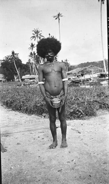 Man with small drum on dirt path