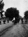 Five men and one woman riding donkeys on dirt road