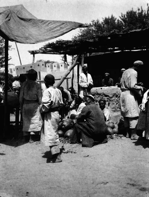 Several men and boy near a shade area and open wooden structure