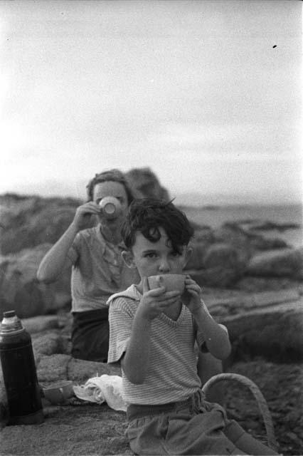 Eleanor and David Lattimore sitting on rocky ledge drinking out of cups