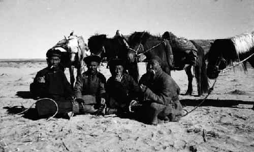 Official delegates sitting on ground in front of horses