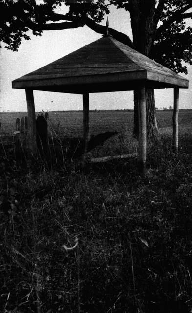 Small open structure over mound and stone marker