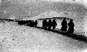 Soldiers walking single-file through snow