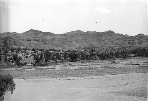 Landscape with village, mountains behind, river in foreground