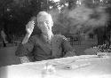 Older man sitting at table, smoking